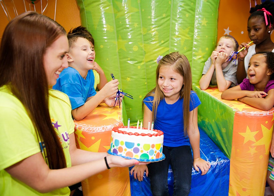 Pump It Up birthday party celebration with birthday child, team member and other kids in the birthday party room.