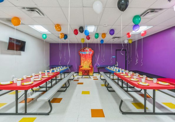 Pump It Up San Jose CA private party room filled with picnic tables, balloons and inflatable throne for birthday child to enjoy cake and pizza.