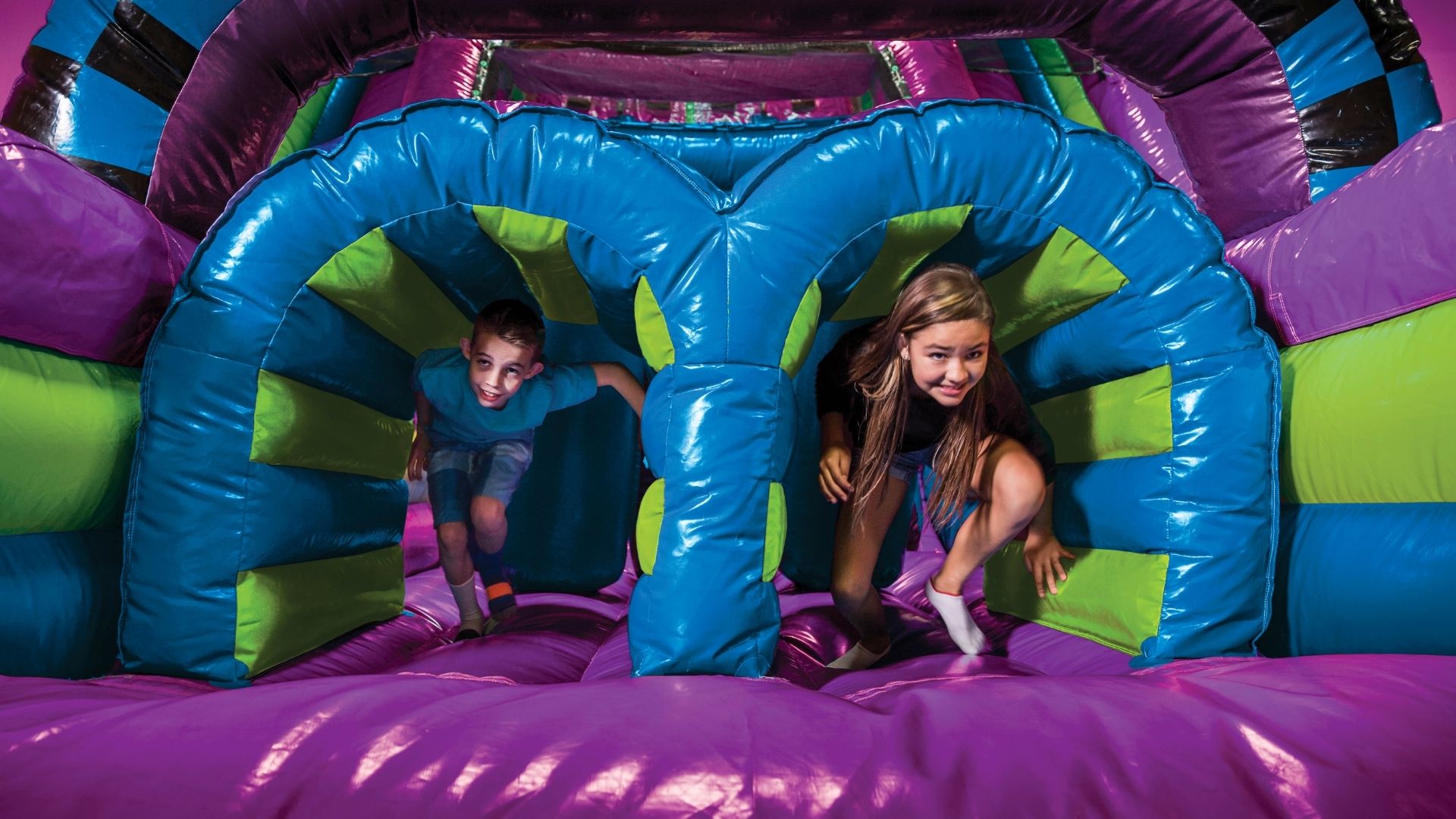 Two kids have fun in a bounce house at a kids birthday party.