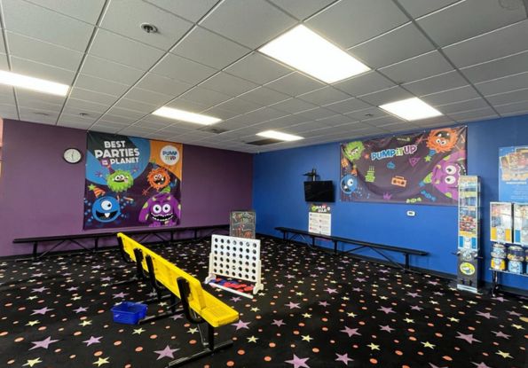 Pump It Up Santa Clara lobby and pre party area for one hundred percent kids private birthday parties. Backdrop for photos and benches for kids to sit and watch the safety video.