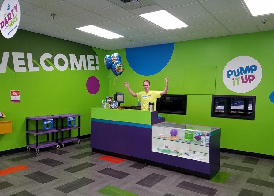 Pump It Up lobby and staff member at the front desk of a kid's birthday party place.